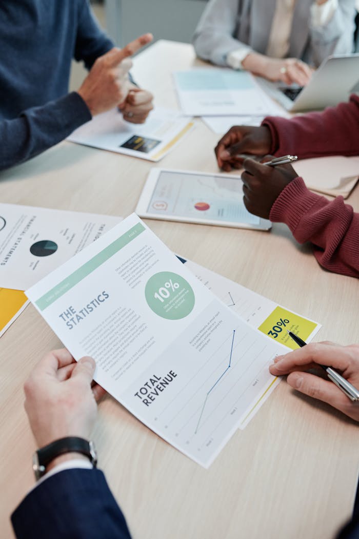 Colleagues discussing financial documents and statistics in an office setting.
