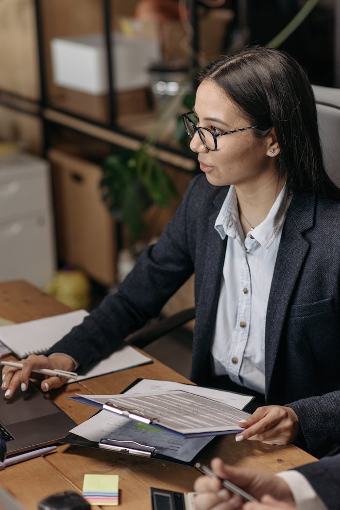 Asian woman in blazer working with documents at office desk. Ideal for business and work themes.